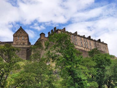 Edinburgh, İngiltere - 17 Ağustos 2019: Edinburg Kalesi'nin güzel havalarda görünümü, kabarık bulutlar ve arka planda mavi gökyüzü. 12 c.'de kurulan, şimdi Edinburgh tanınabilir sembolü