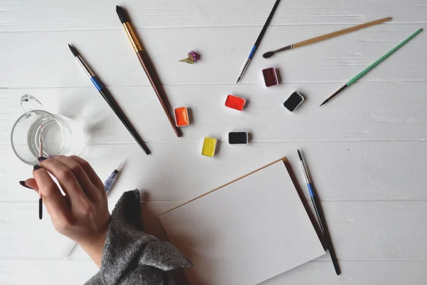 Uma Mulher Pinta Num Caderno Esboços Ferramentas Para Pintar Mesa — Fotografia de Stock