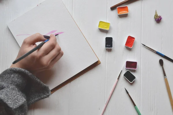 Uma Mulher Pinta Num Caderno Esboços Ferramentas Para Pintar Mesa — Fotografia de Stock