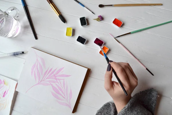 Uma Mulher Pinta Num Caderno Esboços Ferramentas Para Pintar Mesa — Fotografia de Stock