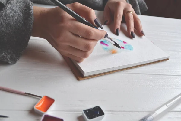 Uma Mulher Pinta Num Caderno Esboços Ferramentas Para Pintar Mesa — Fotografia de Stock