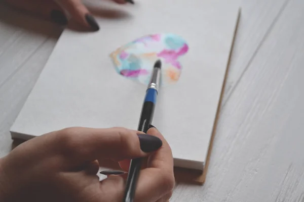 Uma Mulher Pinta Num Caderno Esboços Ferramentas Para Pintar Mesa — Fotografia de Stock