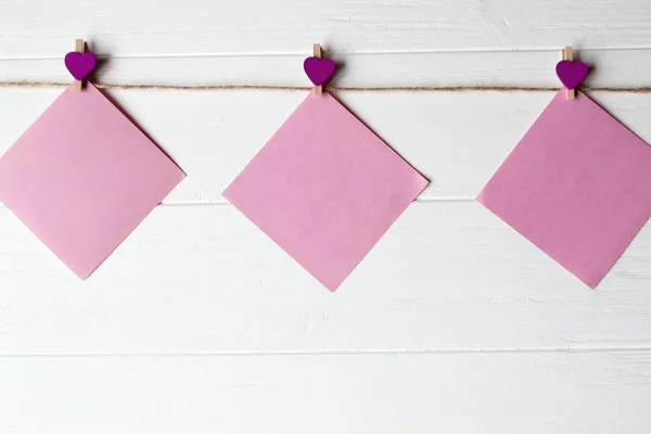 Pink memo sheets fastened with a decorative pin on a white wooden board.