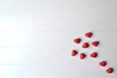Kırmızı şeker kalp ve beyaz tahta masada kırmızı mum şeklinde. Sevgililer günü tebrik kartı için arka plan metin için yer ile.