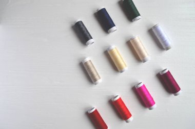 Beyaz arka plan üzerinde renkli iplik bobinleri.