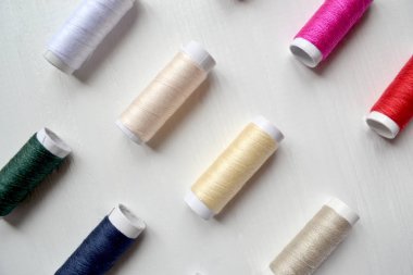 Beyaz arka plan üzerinde renkli iplik bobinleri.