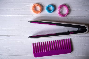 Saç bakım aletleri. Güzellik Salonu. Saç bakım araçları Beyaz ahşap zemin üzerinde. Saç kurutma makinesi, saç maşası, tarak ve parlak sarmal scrunchies.