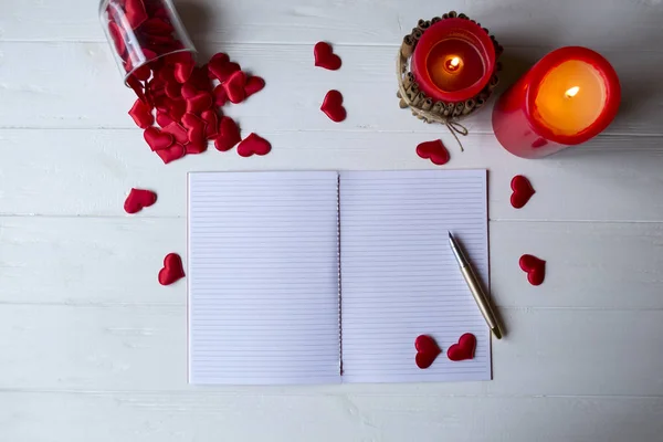 Red candles, love hearts and notebook on the table. Beautiful bckground with copy space.