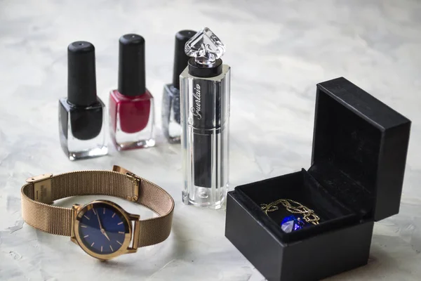 Wrist watch and female accessories on the table.