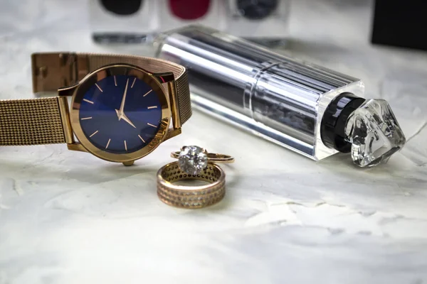 Wrist watch and female accessories on the table.