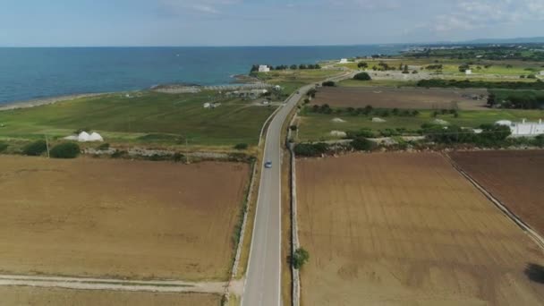Το αυτοκίνητο μέσω του πεδίου κοντά στη θάλασσα στην πτήση Drone Ιταλία 4k — Αρχείο Βίντεο