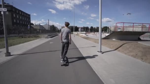 Longboard eléctrico paseo de verano en el estadio deportivo rojo con parque infantil — Vídeos de Stock