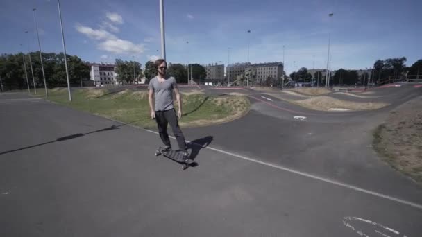 Elektrische Longboard zomer rit op rode sport stadion met speeltuin — Stockvideo