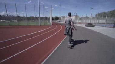 Elektrik Longboard adam kazak ve şapka kırmızı spor Stadyumu Bahçesi ile binmek