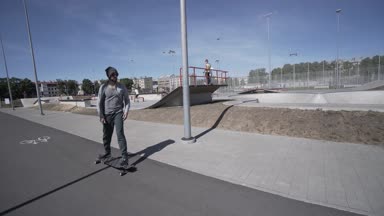 Elektrik Longboard adam yeşil gömlek ve şapka kırmızı spor Stadyumu Bahçesi ile binmek