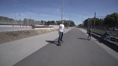 Elektrik Longboard adam beyaz t-shirt ve şapka kırmızı spor Stadyumu Bahçesi ile binmek