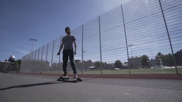 Elektrické Longboard letní jízda na červenou sportovní stadion s hřištěm — Stock video