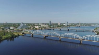 Köprü Riga şehir raylı yollar Slowmotion drone uçuş ile araçların trafik air uçuş daugava Nehri üzerinde bridge yakınındaki tren