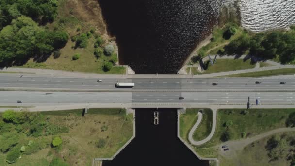 Wiadukt mostu drogowego autostrady w Rydze i budynek z ruchu drogi i samochody Drone lotu w pobliżu wody — Wideo stockowe