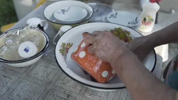 Γιαγιά πλένει τα πιάτα στον ανοιχτό αέρα μέρα του καλοκαιριού — Αρχείο Βίντεο