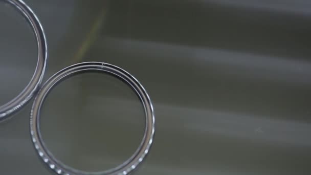Anéis de casamento de prata na mesa de vidro macro closeup atirar jóias de diamantes — Vídeo de Stock
