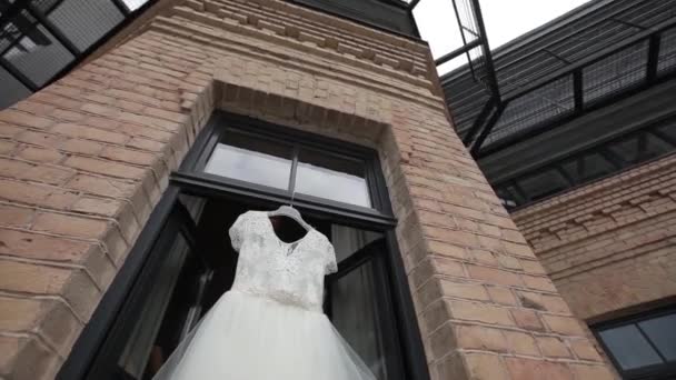 Abito da sposa bianco appeso alle finestre di apertura sul balcone e scene di mattoni — Video Stock