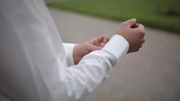 The man puts on cufflinks on a white shirt in the street — Stock Video