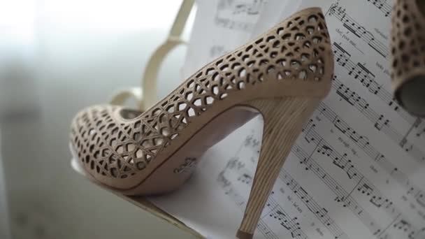 Νυφικά γάμου όμορφα παπούτσια μουσικές νότες σε χαρτί πολυτελείας ψηλοτάκουνα closeup — Αρχείο Βίντεο