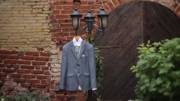 Мужчина в сером пиджаке висит во дворе на вешалке перед свадьбой жениха — стоковое видео