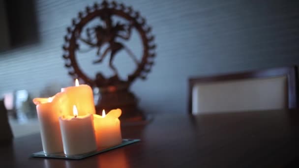 Een beeldje van shiva en kaarsen op een houten tafel — Stockvideo