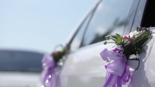 Biały ślub samochód biały kwiatami i wstążkami fioletowy powiesić samochodem — Wideo stockowe