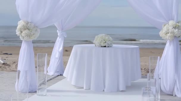 Decorações de casamento de tecidos brancos e flores na praia antes da cerimônia — Vídeo de Stock