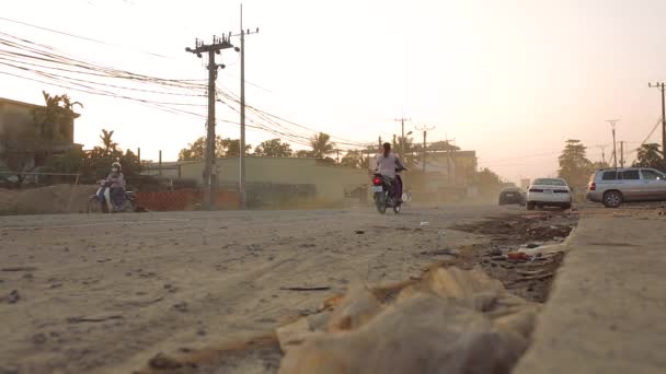 Közúti forgalom Kambodzsában motorkerékpárok és személygépkocsik vezetési egy földúton — Stock videók