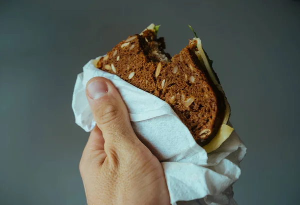 Сэндвич с черным хлебом и хлопьями в мужской руке — стоковое фото