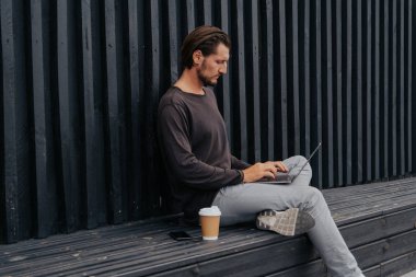 Freelance adam bir laptop telefon kamera ve misik kulaklıklar ile kahve veya çay ile kentsel şehirde siting