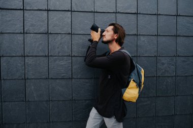 Kamera ve sırt çantası ile genç hipster fotoğrafçı