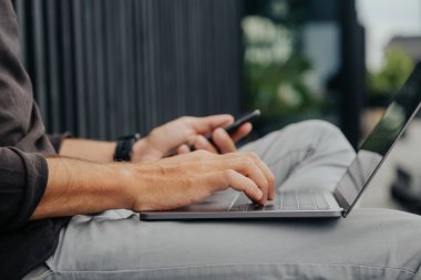 Freelance adam bir laptop telefon kamera ve misik kulaklıklar ile kahve veya çay ile kentsel şehirde siting