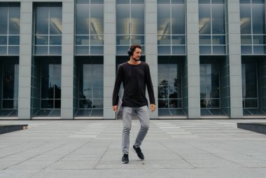 Bir laptop telefon kamera ile çalışan büyük kentsel şehirde Freelancer Man yürüyüş ve kulaklıklar üzerinden müzik dinleme