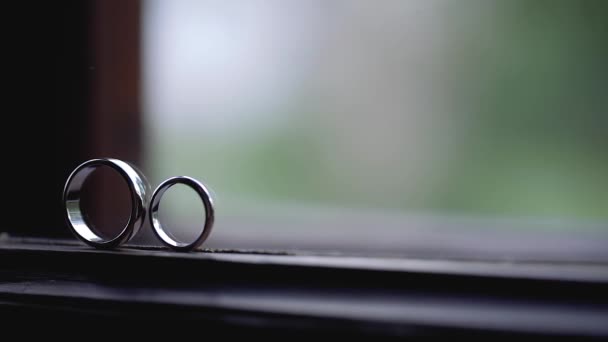 Серебряные обручальные кольца на окне с солнечными лучами световые вспышки макро крупным планом стрелять алмазные украшения — стоковое видео