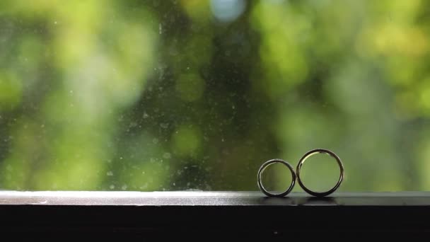 Argent Bagues de mariage sur la fenêtre avec des rayons de soleil fusées éclairantes macro gros plan tige diamon Bijoux — Video