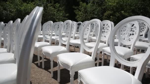 Білі стільці та весільні прикраси з білої та червоної квітів церемонії флористики біля моря — стокове відео
