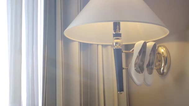 Sapatos brancos pendurar na lâmpada na luz pela parede Macro tiro glidetrack tiro — Vídeo de Stock
