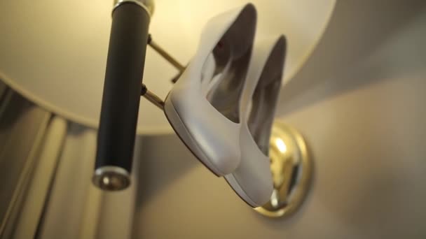 Sapatos brancos pendurar na lâmpada na luz pela parede Macro tiro glidetrack tiro — Vídeo de Stock