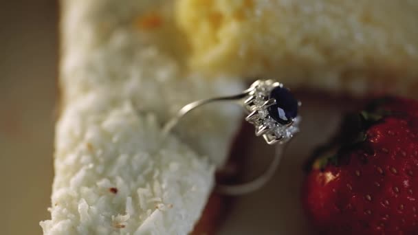 Anéis de casamento de ouro macro closeupin um bolo com coco e morangos jóias de diamante — Vídeo de Stock