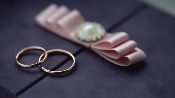 Серебряные обручальные кольца на коробке с розовым бантом макро крупным планом стрелять алмазные украшения — стоковое видео