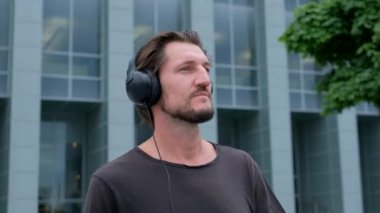 Dinleme müzik Freelancer Man büyük şehir bir dizüstü telefon kamera ve kulaklık ile çalışan