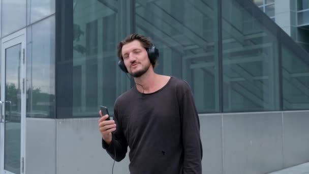 Ascoltare musica Freelancer Man nella grande città urbana lavorando con una fotocamera del telefono portatile e cuffie — Video Stock