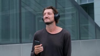 Dinleme müzik Freelancer Man büyük şehir bir dizüstü telefon kamera ve kulaklık ile çalışan