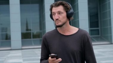 Dinleme müzik Freelancer Man büyük şehir bir dizüstü telefon kamera ve kulaklık ile çalışan