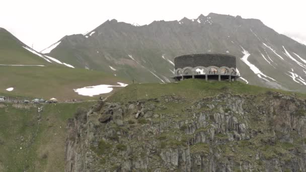 Berg i Georgien Kazbegi och monument med turister norra Kaukasus drönare flygning — Stockvideo